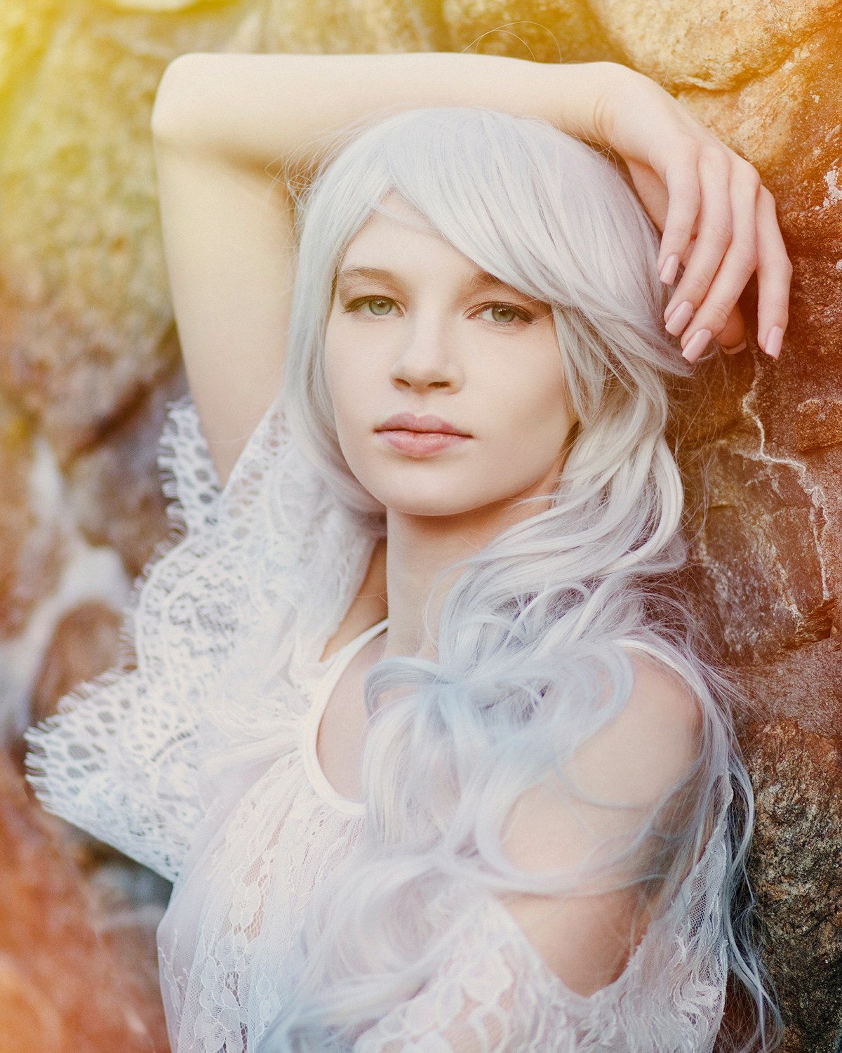 Woman with long silver hair in white lace in warm light, looking at the camera, photographed by Annie Watson in her Naples studio